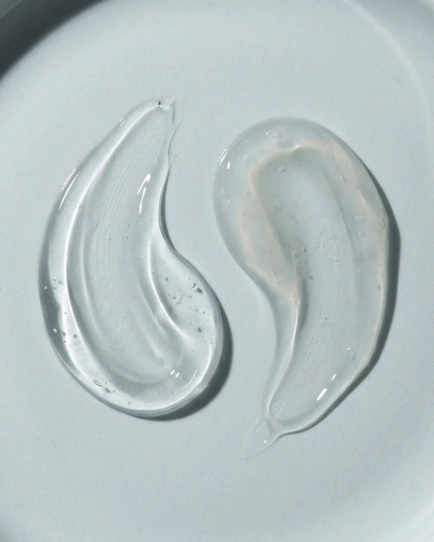 Hair Shampoo and Hair Conditioner texture macro of two clear gel-like substances on a light gray background