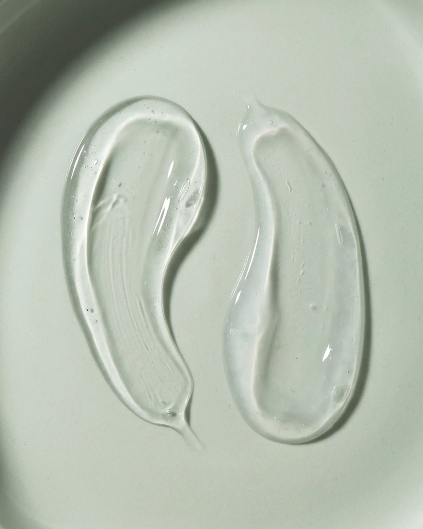 Two clear gel-like substances on a light gray background