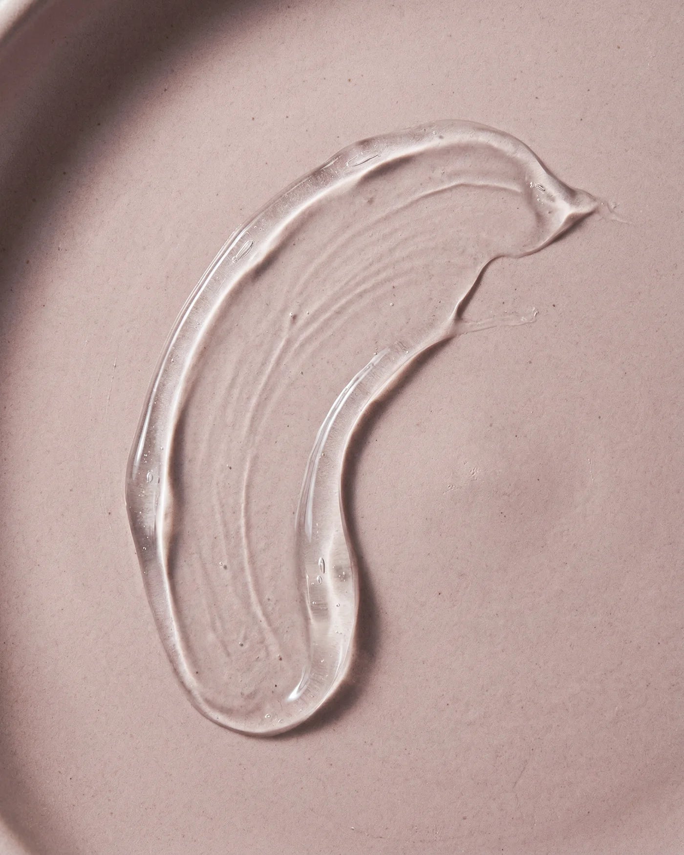 Texture macro of René Fris Anti-Frizz Shampoo. Clear gel on a pink background